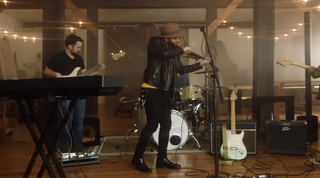 Austin james performing on his violin with his band in a barn for a freestyle libre ad filmed by ASL Productions